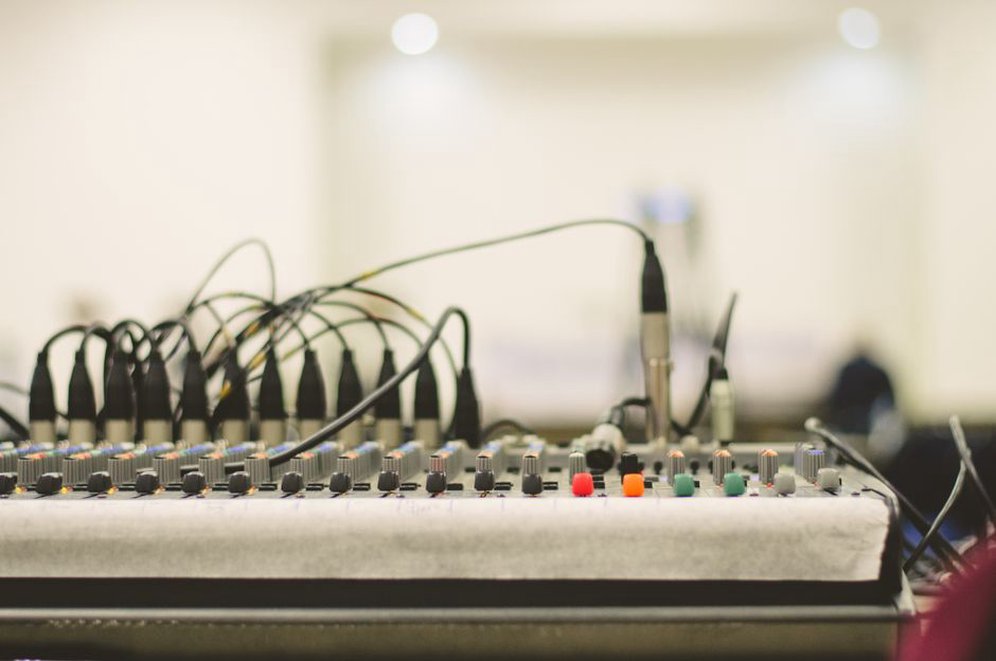Out-of-focus image of audio mixer controls with cables plugged in