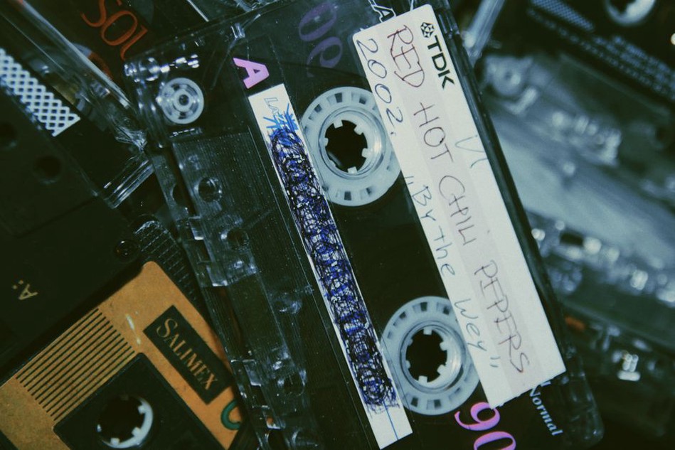 Close-up of a cassette tape with a peeling sticker exposing handwritten kanji text
