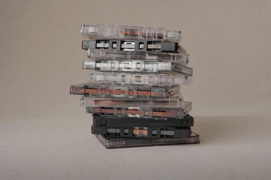 collection of cassette tapes arranged on a shelf in dim light