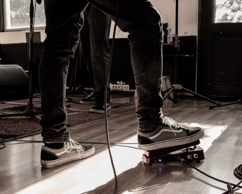 A guitar rests beside an amplifier in an empty room
