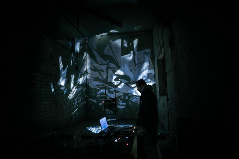 Cables and projected shapes share a dark stage