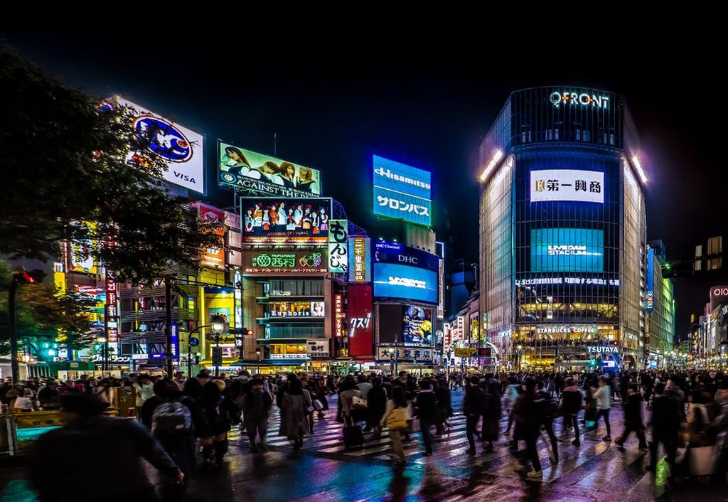 pedestrians crossing Shibuya scramble under layers of glowing signage