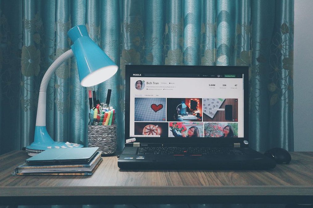 A lamp lights the desk beside a window